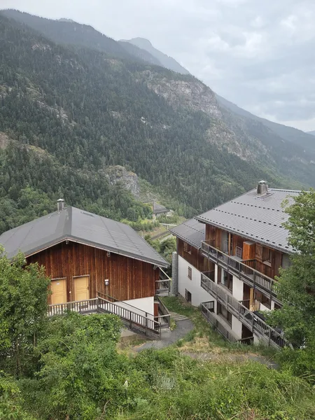 La résidence du Hameau des Eaux d'Orelle en été, chalets en bois face à la montagne